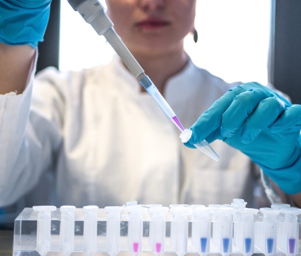 A person wearing a lab coat and medical gloves, organizing samples.