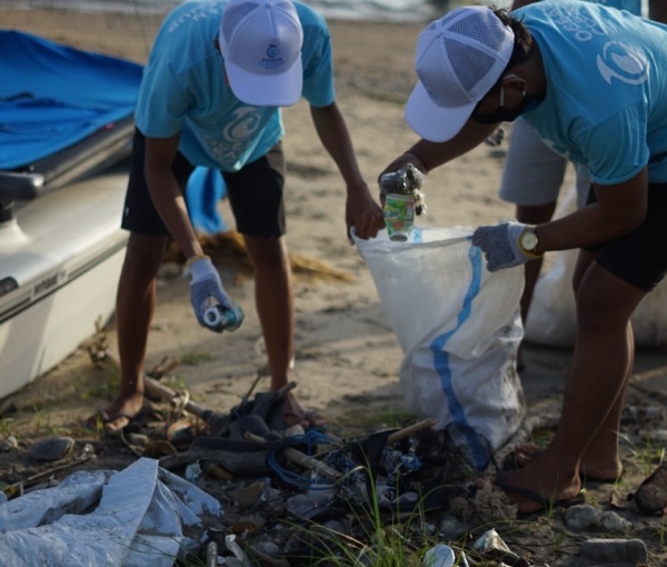 Two people cleaning up garbage on a beach.