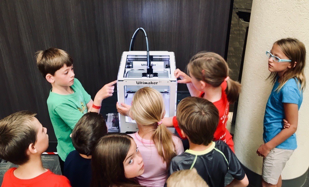 Children observing a 3D printer at work.