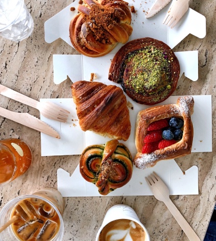 A table top covered with fresh various pastries and beverages.